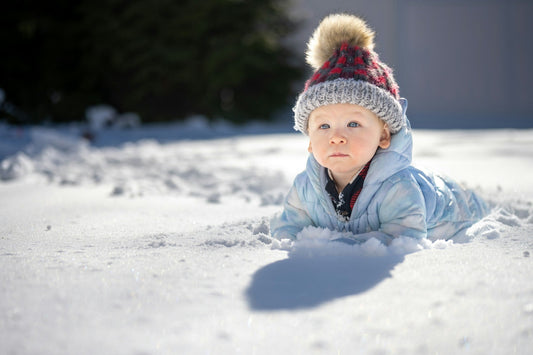 Bébé habillé chaudement allongé dans la neige, regard curieux