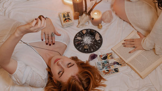 Femme allongée avec cartes de tarot, bougies et roue zodiacale.